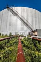 Abandoned Oil Refinery Gas Tank and Rusty Pipeline