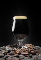 Dark Black Stout Beer Pint Over a Pile of Cocoa Nibs and Beans
