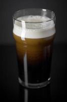 Draft Nitrogen Fresh and Creamy Black Stout Beer Pint over Black Background photo
