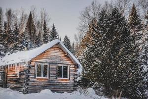 Cabaña de madera de troncos redondos canadienses durante el invierno foto