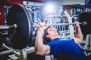 Man pressing barbell on incline bench. photo