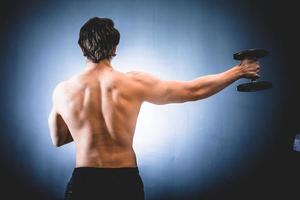 Sportsman with dumbbell in outstretched hand photo