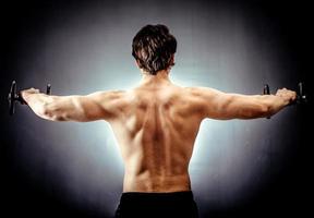 Muscular man doing shoulders exercise with barbell photo