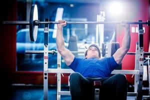 Hombre haciendo press de banca en el gimnasio foto