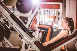 mujer deportiva, entrenamiento, piernas, en, máquina foto