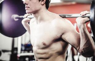 Crop man squatting with barbell photo