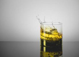 Splashing Glass of Single Malt Whisky over Gray Background photo