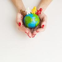top view hands holding globe with people figurines photo