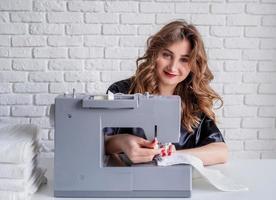 Mujer cosiendo ropa en la máquina de coser en casa