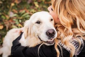 A blond woman hugging her retriever dog in the park photo