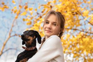 teenager girl holding her dachshund dog in her arms outdoors photo