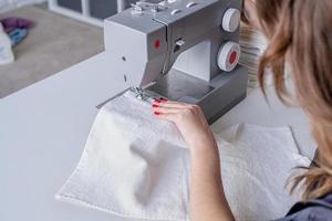 Mujer cosiendo ropa en la máquina de coser en casa foto