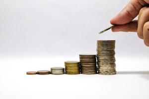 Male hand putting coins tacking  and growing the saving money and business with white background concept. photo