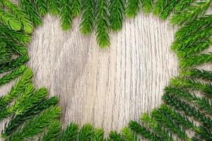Hoja de pino verde en forma de corazón en madera clara para el fondo y la textura. Se utiliza para decorativos para publicidad en línea y concepto de feliz Navidad. foto