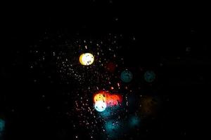 Red blue and yellow light bokeh dots on dark background which its come from behind light car during raining and traffic jam. photo