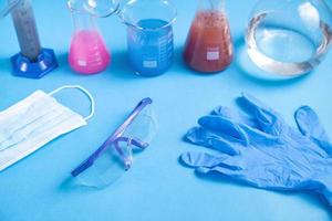 Science glassware with colored liquid gloves and glasses.