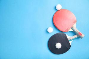 raquetas de tenis de mesa y pelotas de plástico blancas sobre un fondo azul. foto