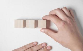 Hand holding wooden cube on a white desk. photo