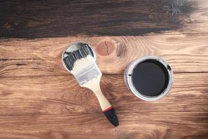 Black paint and brush on wooden background. photo