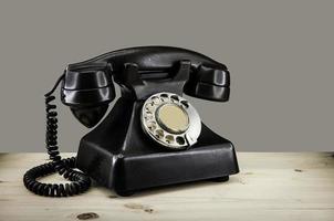 Old vintage phone with rotary disc on wooden table grunge background photo