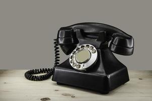 Old vintage phone with rotary disc on wooden table grunge background photo