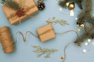 composición plana de navidad con envoltura de regalo. abeto y ramitas doradas, adornos, guirnaldas sobre un fondo azul. vista desde arriba foto