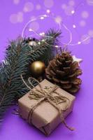 composición navideña de ramas de abeto, regalo, juguetes navideños, guirnaldas sobre un fondo morado. foto de concepto vacaciones de navidad y año nuevo, regalos.