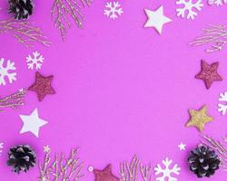 Christmas flat lay with empty place for text. Golden twigs, stars, snowflakes, cones on a pink background. photo