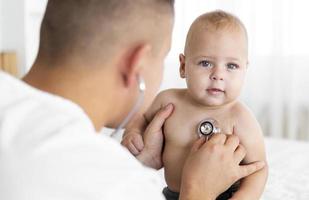 back view doctor listening little baby with stethoscope photo
