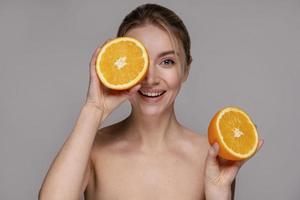 beautiful woman holding halved orange
