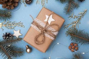 Christmas present with decor. Concept photo Christmas gift, New Year preparation. Fir tree and golden twigs, decorations, garlands on a blue background.