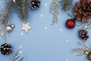 endecha plana de navidad. concepto foto regalo de navidad, año nuevo. abeto y ramitas doradas, adornos, guirnaldas sobre un fondo azul. copia espacio