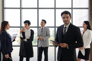 portrait of young caucasian businessman with background of colleagues photo