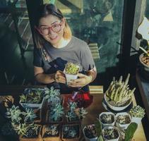 toothy smiling face of asian woman holding pot of succulent at home terrace photo