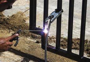 un trabajador está soldando hierro sin usar guantes. trabajos de soldadura ligeros. foto