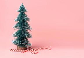 ree Christmas tree with candy cane on pastel pink studio background