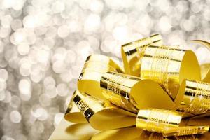 Close up Golden present box with big bow at bokeh white blur background photo