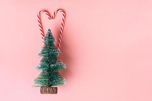 ree Christmas tree with candy cane on pastel pink studio background photo