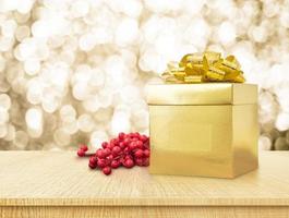 Caja de regalo de oro y cinta sobre mesa de madera con oro brillante foto