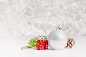 Bola brillante de Navidad blanca y caja de regalo en mesa blanca en bokeh azul brillante foto