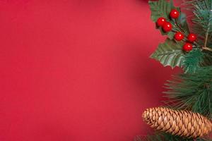 Christmas decoration and fir branches wreath with cherry and pine cone on red table photo