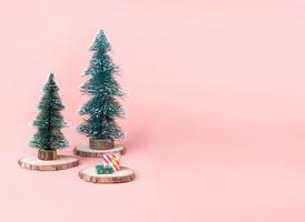 Árbol árbol de Navidad en rodajas de troncos de madera con caja actual en rosa pastel foto