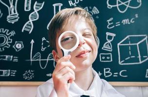Little boy looking at camera through magnifying glass photo