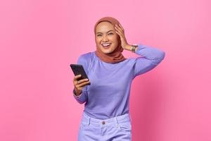 retrato, de, sonriente, joven, mujer asiática, tenencia, teléfono móvil, en, fondo rosa