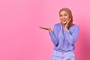 Retrato de mujer asiática joven sonriente que muestra el espacio de la copia en la palma aislada sobre fondo de color rosa foto