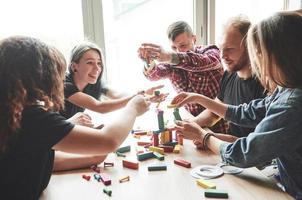 A group of creative friends sitting on a wooden table. People were having fun while playing a board game. photo