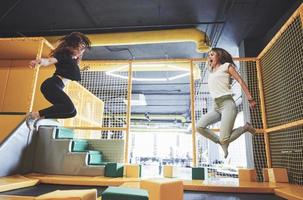 The company is a young woman who has fun with soft blocks on a children's playground in a trampoline center. photo