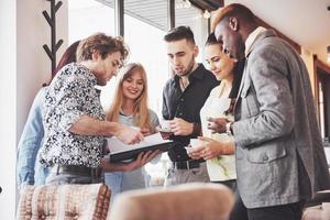 Successful business people are using gadgets, talking and smiling during the coffee break in office photo