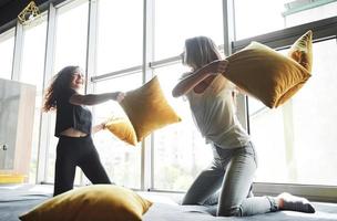 Merry happy girlfriends are fighting with pillows. photo