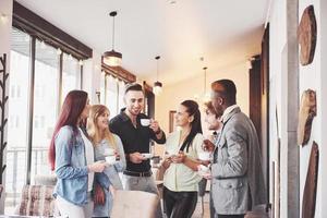 Successful young business people are talking and smiling during the coffee break in office photo